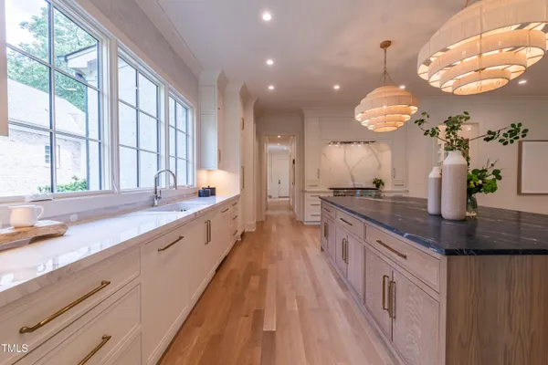 a large kitchen with granite countertop a large counter top a sink a window and stainless steel appliances