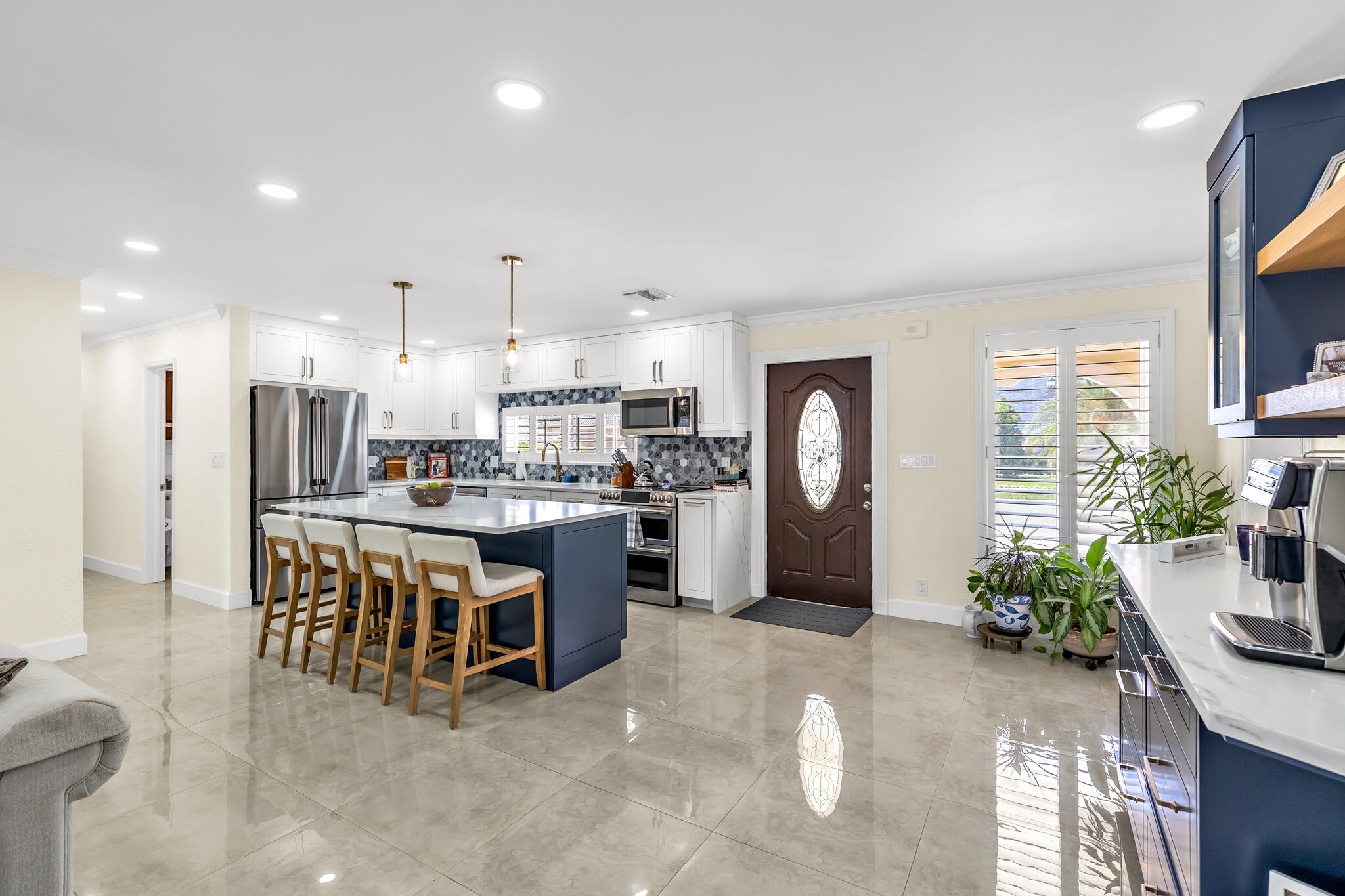 4920 Northeast 28th Avenue Lighthouse Point, FL 33064 - Photo 16 of 38 a kitchen with stainless steel appliances kitchen island granite countertop a refrigerator a stove a sink a dining table and chairs with wooden floor