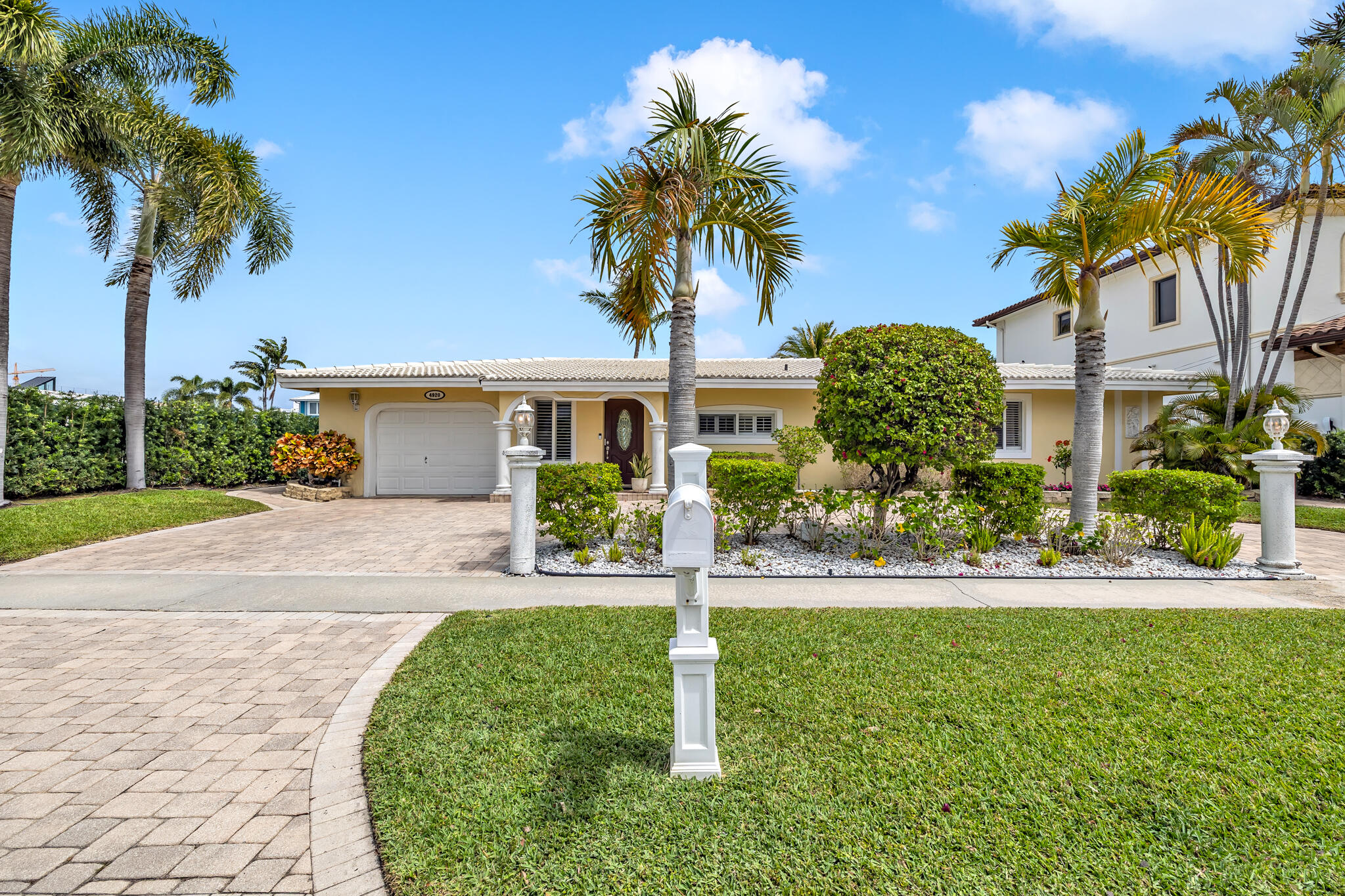 4920 Northeast 28th Avenue Lighthouse Point, FL 33064 - Photo 5 of 38 a front view of a house with a yard and palm trees