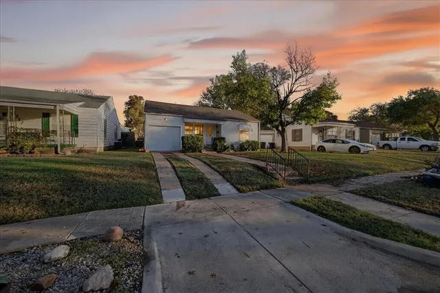 a view of a white house next to a yard with big trees