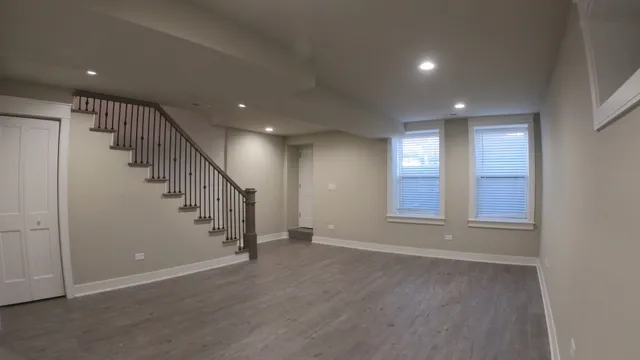 a view of an empty room with wooden floor and stairs
