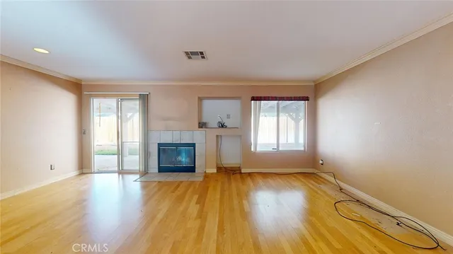 an empty room with wooden floor fireplace and windows