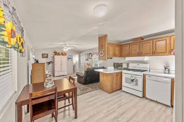 a open kitchen with stainless steel appliances granite countertop a stove top oven a sink dishwasher and white cabinets with wooden floor