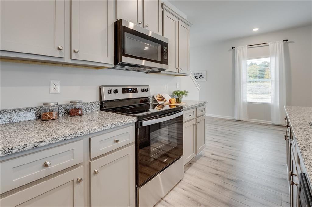 7443 Knoll Hollow Road Lithonia, GA 30058 - Photo 22 of 46 a kitchen with granite countertop white cabinets appliances a sink and a window