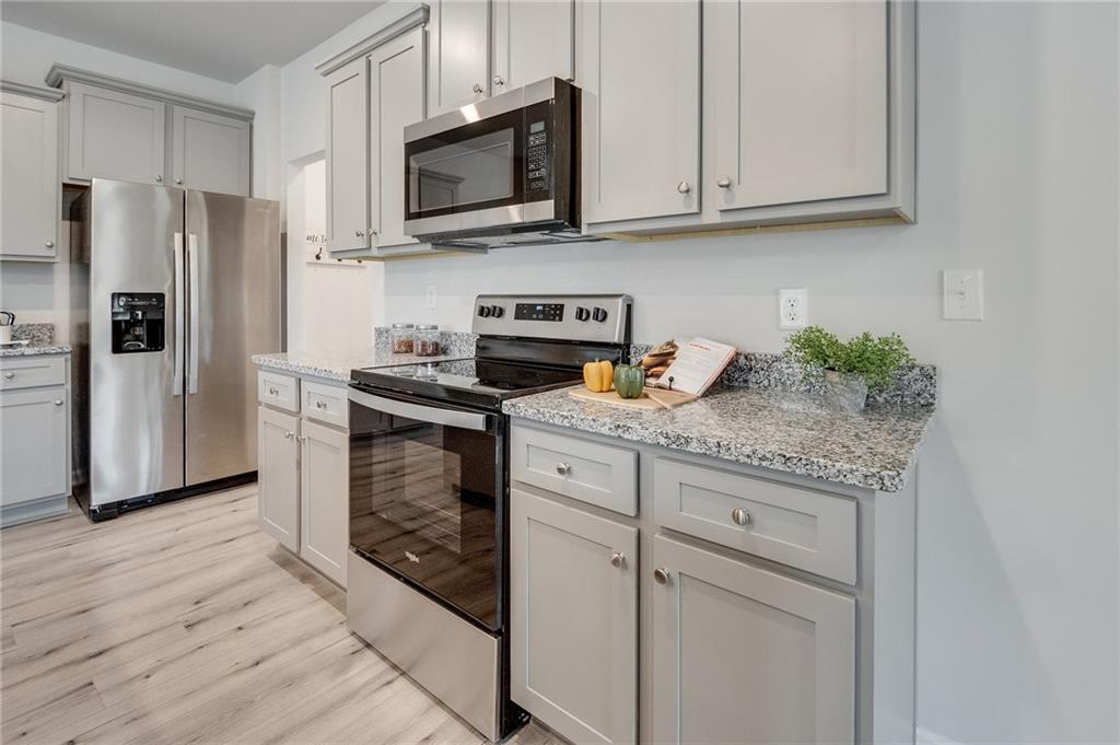 7443 Knoll Hollow Road Lithonia, GA 30058 - Photo 23 of 46 a kitchen with granite countertop a refrigerator stove and microwave