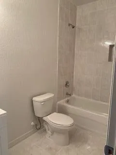 a white toilet sitting next to a bath tub and a shower