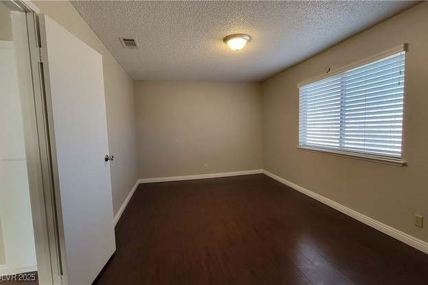 1016 Vantage Point Road Las Vegas, NV 89128 - Photo 9 of 18 Spare room with dark wood-type flooring, baseboards, visible vents, and a textured ceiling