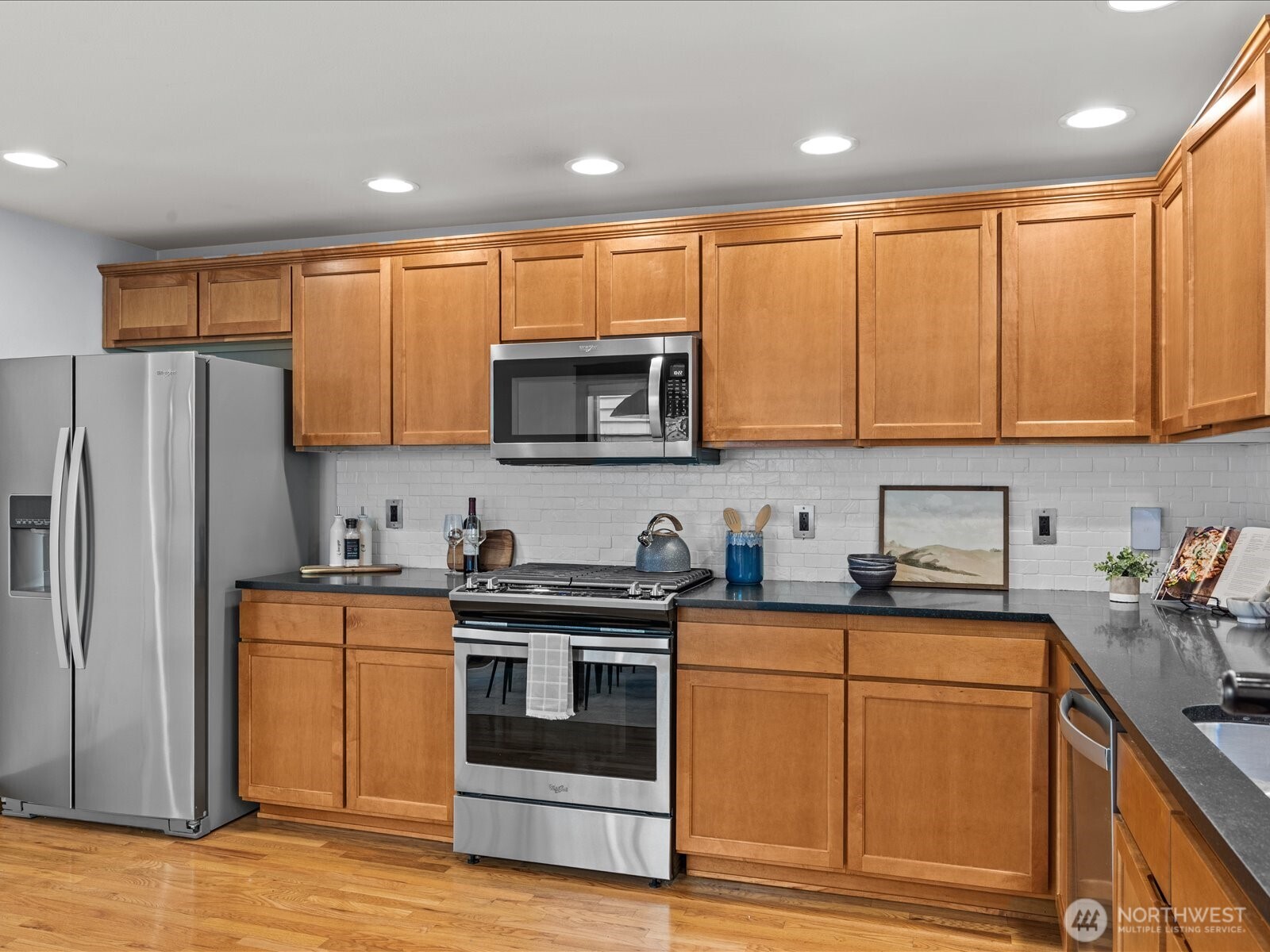 3018 Southwest Hinds Street Seattle, WA 98126 - Photo 12 of 27 a kitchen with stainless steel appliances granite countertop a refrigerator a stove top oven a sink and dishwasher with wooden floor