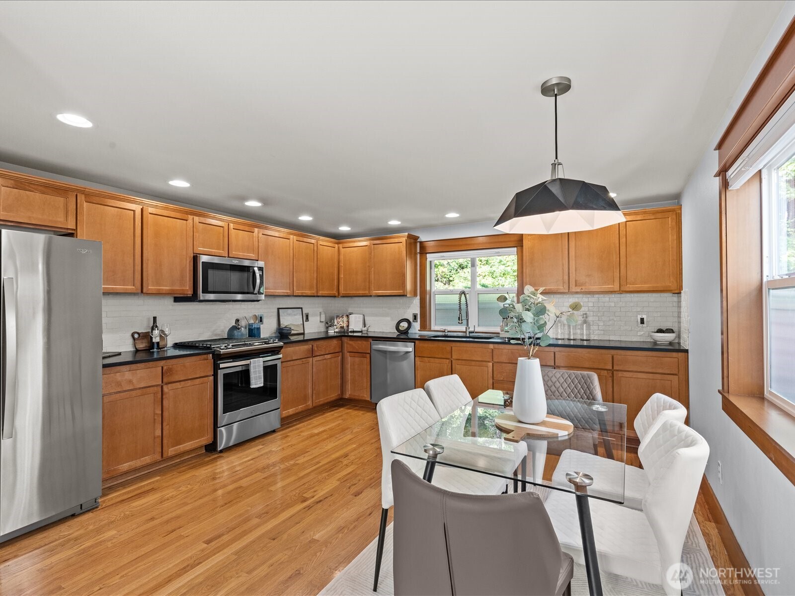 3018 Southwest Hinds Street Seattle, WA 98126 - Photo 10 of 27 a kitchen with stainless steel appliances granite countertop a stove top oven a sink dishwasher a dining table and chairs with wooden floor