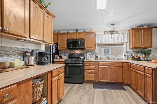a kitchen with stainless steel appliances granite countertop a stove a sink dishwasher and a microwave oven with wooden floor