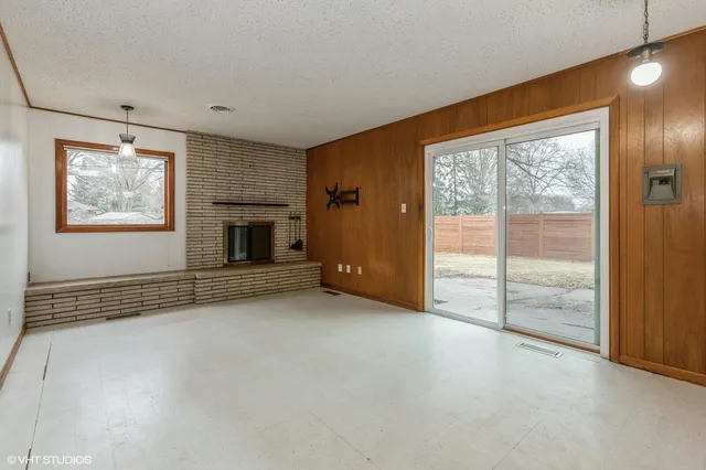 an empty room with windows and fireplace