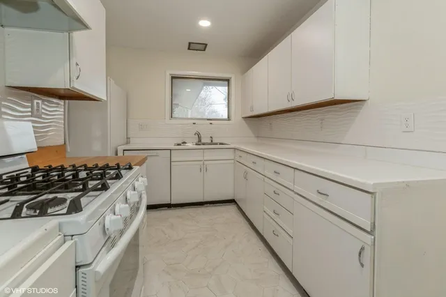 a kitchen with white cabinets and appliances