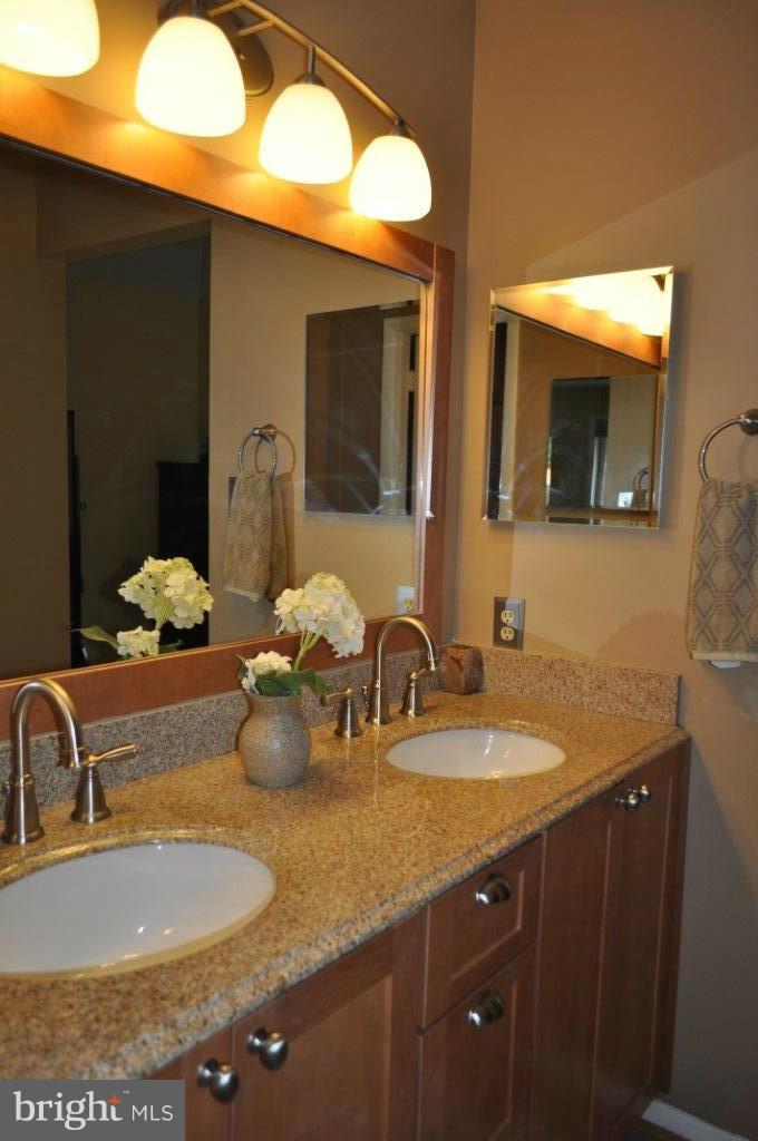 5565 Suffield Court Columbia, MD 21044 - Photo 25 of 30 a bathroom with a granite countertop sink a large mirror and vanity