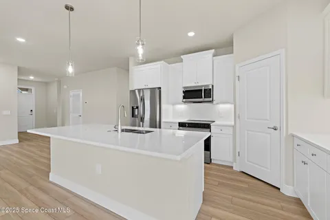 a kitchen with a sink a counter top space and a view of living room