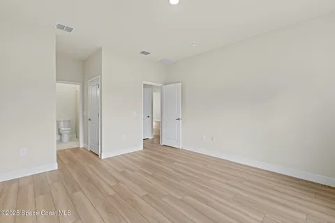 a view of an empty room with wooden floor and windows