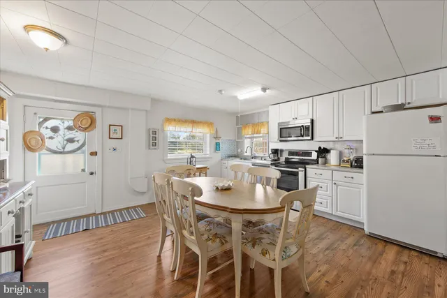 a kitchen with stainless steel appliances granite countertop a dining table chairs refrigerator and cabinets