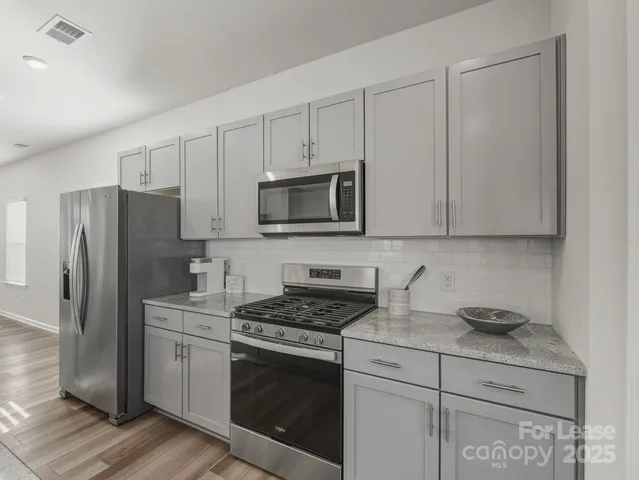 a kitchen with granite countertop white cabinets stainless steel appliances and a sink