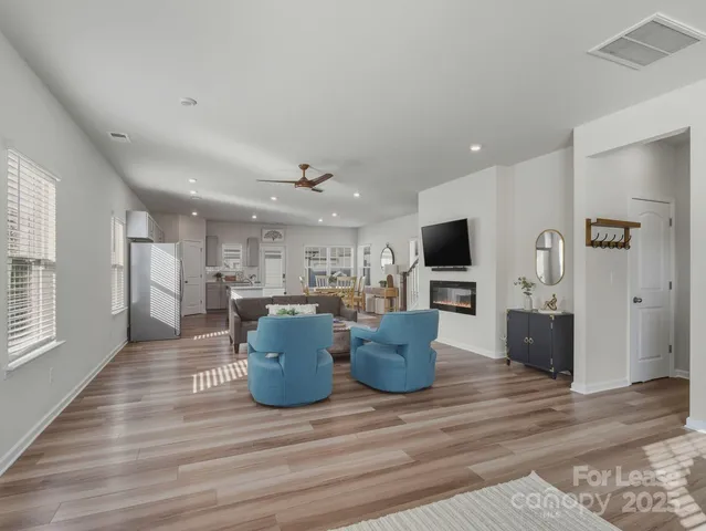 a living room with furniture a flat screen tv and kitchen view