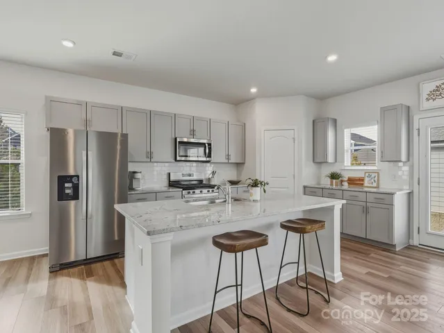 a kitchen with refrigerator a stove a sink and chairs