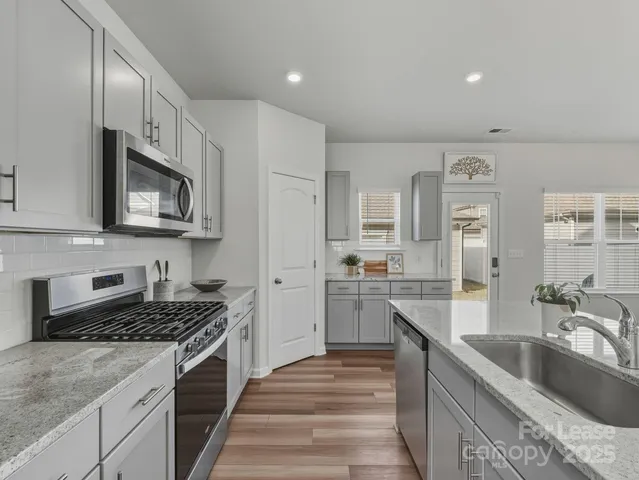a kitchen with stainless steel appliances granite countertop a sink stove and refrigerator