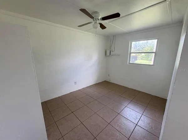 an empty room with windows and fan