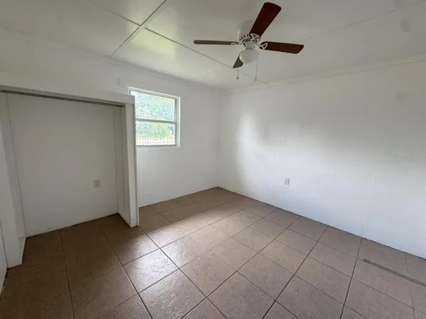 an empty room with a ceiling fan and carpet