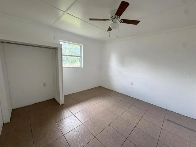an empty room with a ceiling fan and carpet