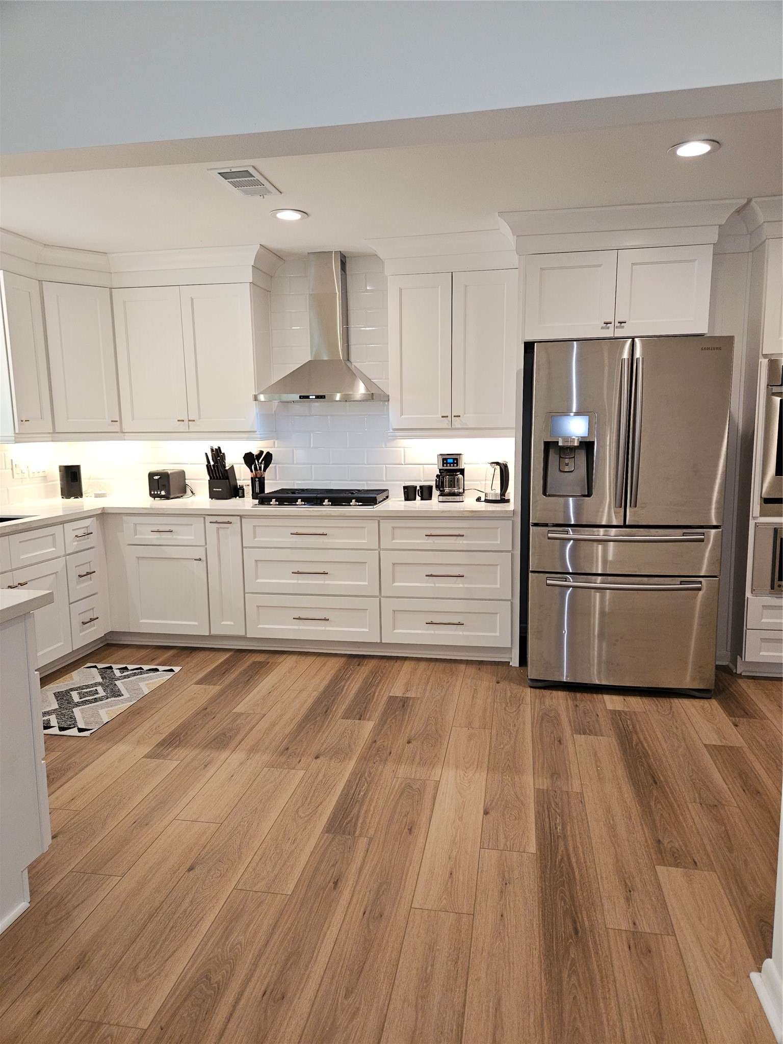 a kitchen with granite countertop a refrigerator oven a sink a cabinets and wooden floor