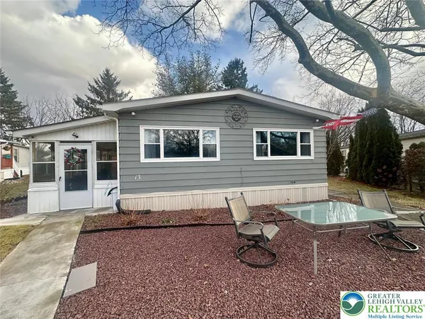 a view of a house with backyard sitting area and covered with trees