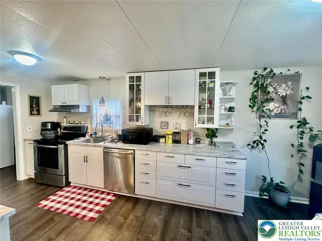 a kitchen with stainless steel appliances a stove a sink cabinets and a wooden floor