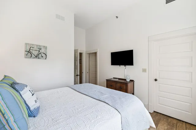 a bedroom with a bed and a flat tv screen on the dresser
