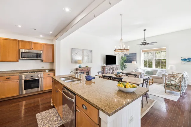 a open kitchen with stainless steel appliances granite countertop a sink dishwasher a stove with a dining table and chairs with wooden floor