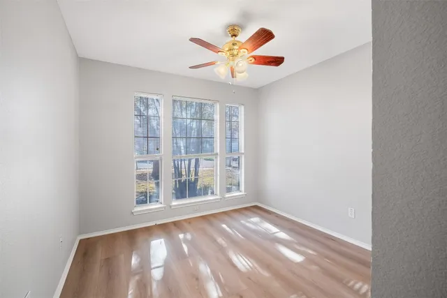 an empty room with window and ceiling fan