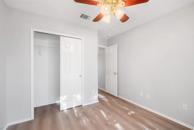 wooden floor in an empty room with a chandelier fan