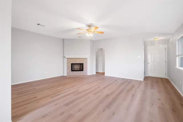 a view of empty room with wooden floor and fan