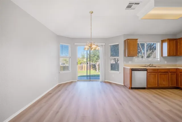 a kitchen with granite countertop wooden floors white cabinets and stainless steel appliances