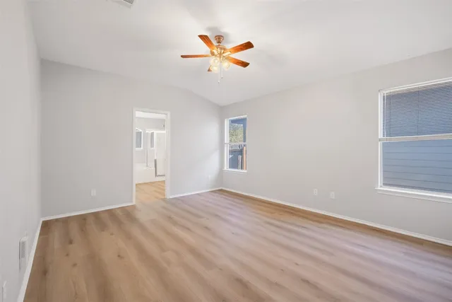 an empty room with wooden floor and a ceiling fan