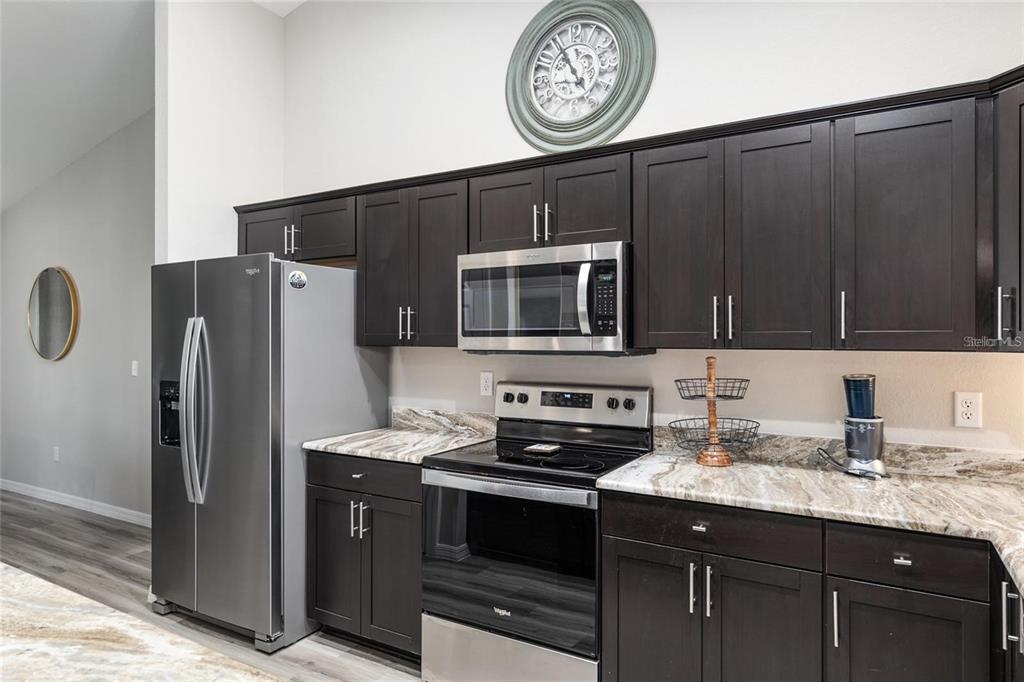 9947 Southeast 117th Street Road Belleview, FL 34420 - Photo 14 of 44 a kitchen with stainless steel appliances granite countertop a refrigerator and a stove top oven