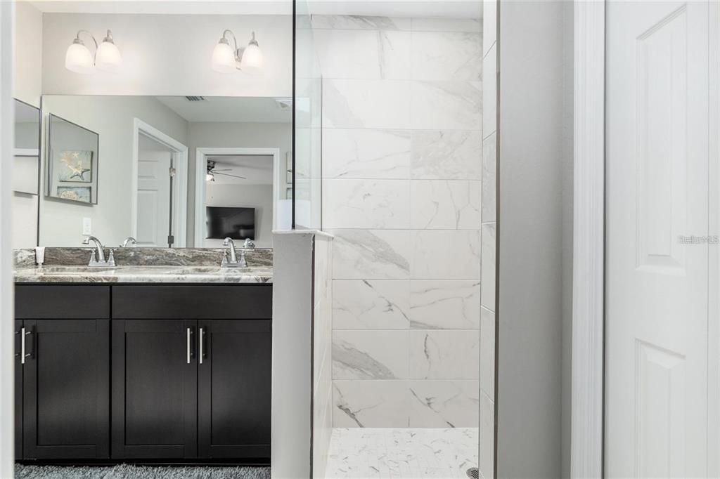 9947 Southeast 117th Street Road Belleview, FL 34420 - Photo 25 of 44 a bathroom with a granite countertop sink a mirror and shower