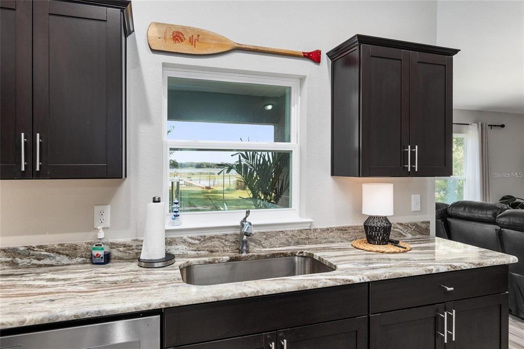 9947 Southeast 117th Street Road Belleview, FL 34420 - Photo 10 of 44 a kitchen with granite countertop a sink and a wooden cabinets