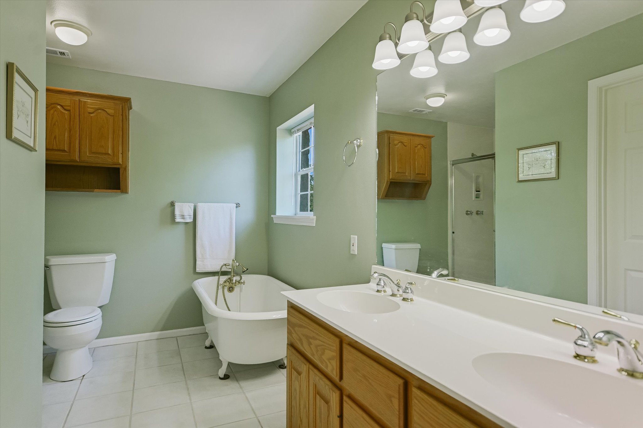 401 North Rainbow Ranch Road Wimberley, TX 78676 - Photo 21 of 39 An inviting bathroom displays a classic clawfoot tub alongside a double vanity and tile flooring.