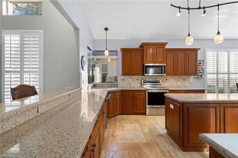 a large kitchen with stainless steel appliances granite countertop a stove a sink dishwasher a microwave oven with cabinets and wooden floor