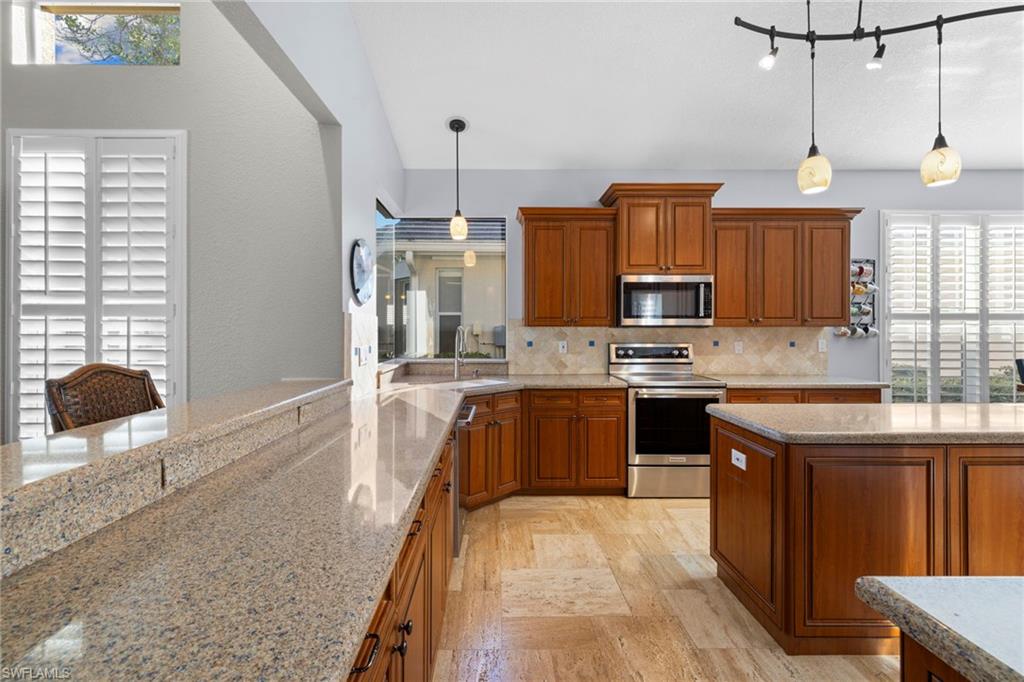 1845 Pondside Lane Naples, FL 34109 - Photo 19 of 47 a large kitchen with stainless steel appliances granite countertop a stove a sink dishwasher a microwave oven with cabinets and wooden floor