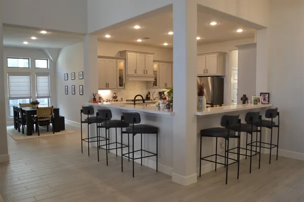 a kitchen with kitchen island a dining table chairs and white cabinets