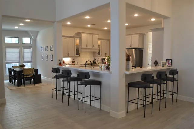 a kitchen with kitchen island a dining table chairs and white cabinets