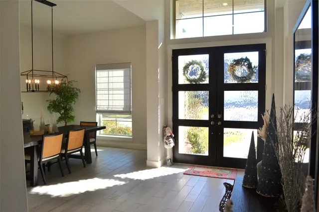 a dining room with wooden floor a chandelier a wooden table and chairs