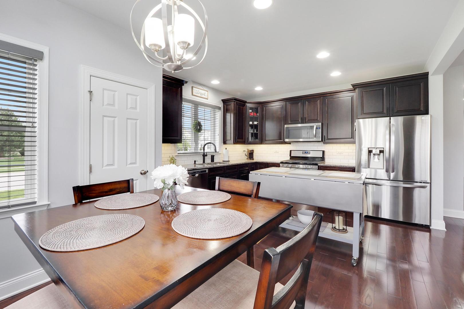 1266 Falcon Ridge Drive Elgin, IL 60124 - Photo 10 of 28 a kitchen with stainless steel appliances granite countertop a sink a stove a kitchen island with chairs and wooden floor