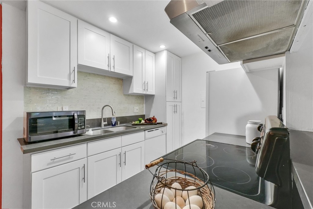 1030 West MacArthur Boulevard, Unit 5 Santa Ana, CA 92707 - Photo 9 of 26 a kitchen with stainless steel appliances granite countertop a sink a stove white cabinets and chairs
