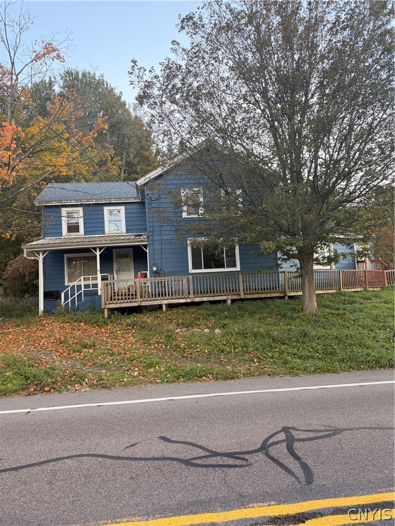 2025 Apulia Road LaFayette, NY 13084 - Photo 2 of 16 A multi-level wood-sided exterior features elevated decks alongside a grassy roadside lot.