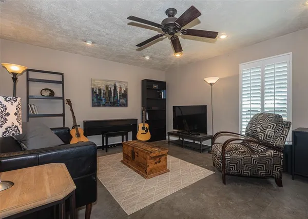 a living room with furniture a ceiling fan and a flat screen tv